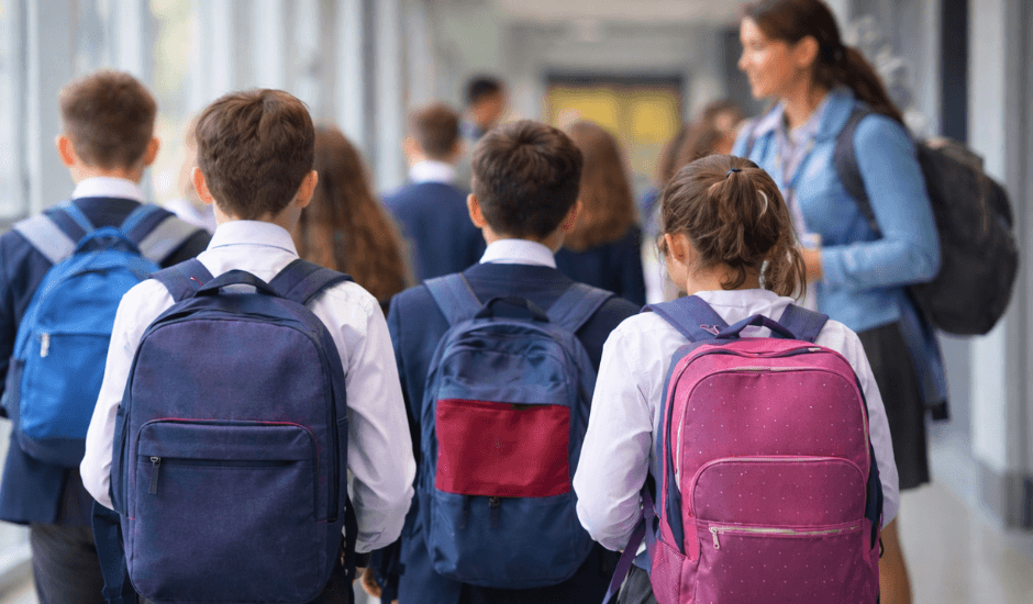 UK school children in uniform walking through a school hallway, illustrating the importance of Keeping Children Safe in education.