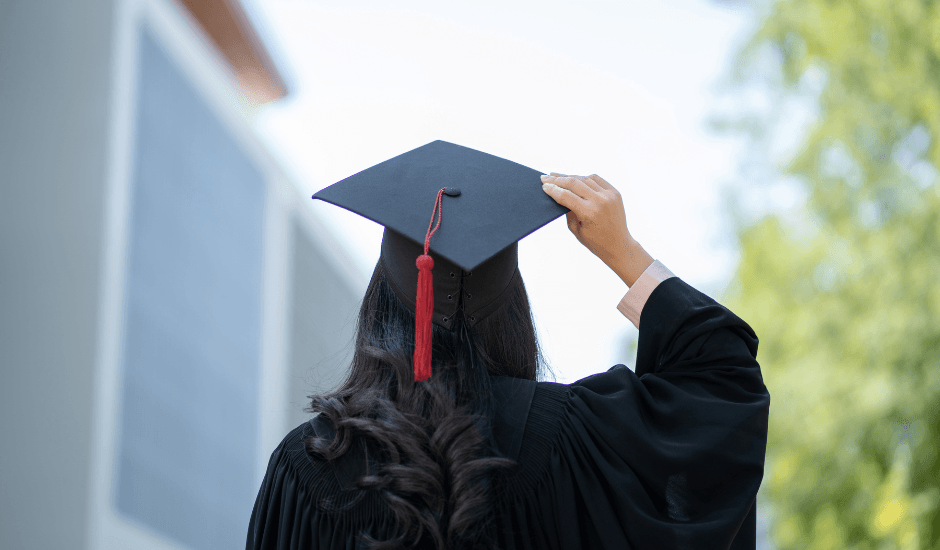 A newly qualified teacher in graduation cap and gown on a university campus, about to start their ECT induction